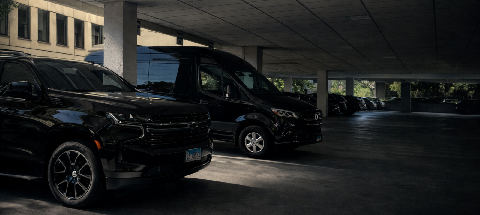 Luxury SUV and executive van departing a modern office building, premium chauffeur transportation service
